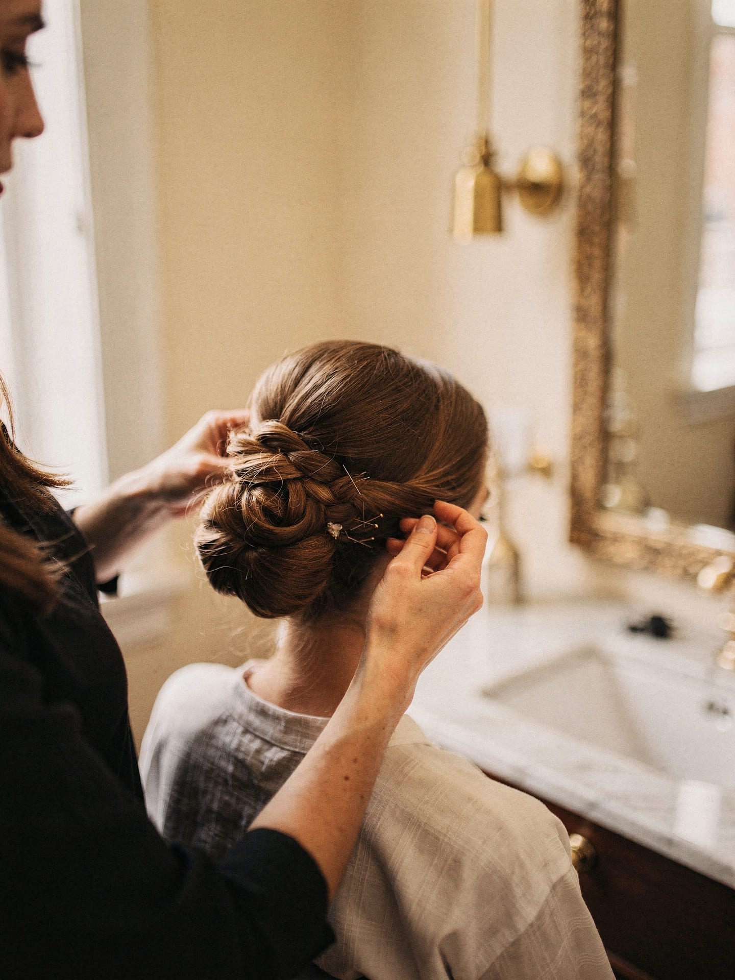 An elegant special-occasion updo being finished by hand